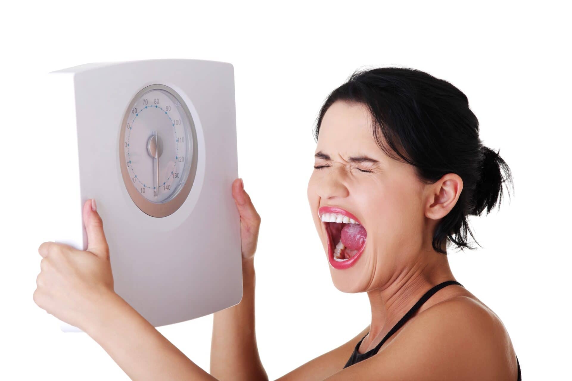 A woman holding up a set of bathroom scales and shouting at them in frustration